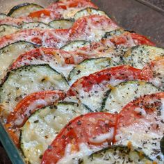 a casserole dish with zucchini, tomatoes and cheese on it is ready to be eaten