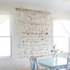 a dining room table with two chairs and a wall hanging made out of seashells