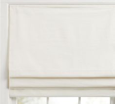 an open window with a white roman blind