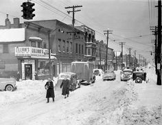 an old black and white photo of people walking in the snow on a city street