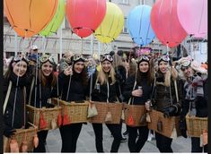 a group of women standing next to each other holding balloons