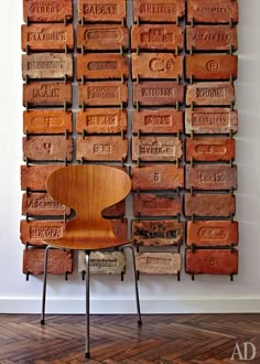 a wooden chair sitting in front of a wall made out of old brick blocks with writing on them