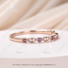 a pink sapphire and white diamond ring on top of a white surface with the words bebegem written below it