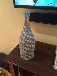 a glass vase sitting on top of a wooden table next to a tv screen and bookcase