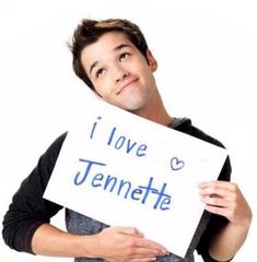 a young man holding up a sign that says i love jennyette with blue writing on it