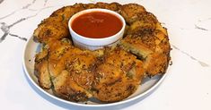 a white plate topped with bread rings covered in ketchup on top of a table