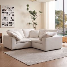 a living room with a large white sectional couch and rugs on the wooden floor