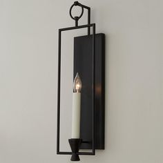 a candle is lit on the wall next to a mirror with a light in it