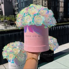 a person holding up a pink box with flowers on it and the words dose of roses written in white