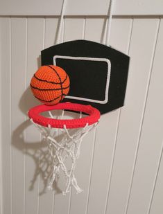 an orange and black basketball is in the air above a red and white hoop on a wall