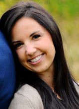 a smiling woman with long dark hair and brown eyes is leaning against a blue pillow