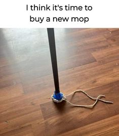 a blue mop sitting on top of a wooden floor next to a black pole