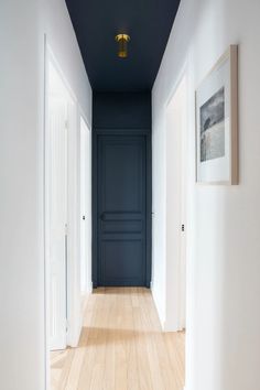 an empty hallway with blue walls and wooden floors