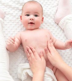 a baby laying on its back being held by two hands