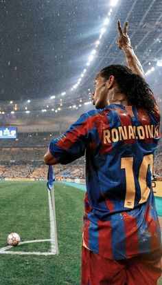 a soccer player waves to the crowd as he stands in front of an empty stadium