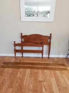 a wooden bed frame sitting on top of a hard wood floor next to a mirror