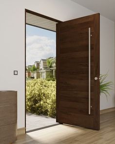 an open wooden door in front of a white wall and wood flooring with a potted plant next to it