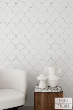 a white chair sitting next to a table with two vases on top of it