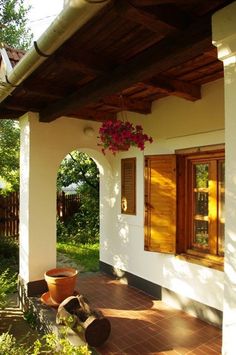 a porch with potted plants and wooden shutters