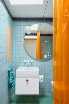 a bathroom with blue and green tiles on the walls, toilet, sink and mirror