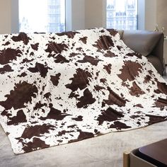 a brown and white cow print blanket sitting on top of a couch