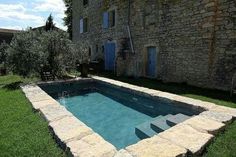 an empty swimming pool in front of a stone building