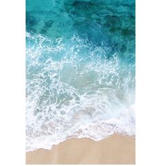 an aerial view of the ocean waves and sand