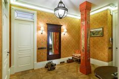 an entry way with a lamp and mirror on the wall next to a bench in front of a door