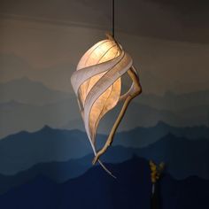 a lamp hanging from a ceiling in a room with mountains and blue sky behind it