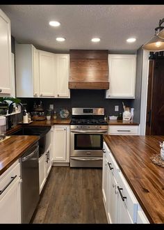 a kitchen with white cabinets and wood counter tops, an oven and dishwasher