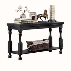 a black table with books, vase and pictures on it's shelf next to a wicker basket