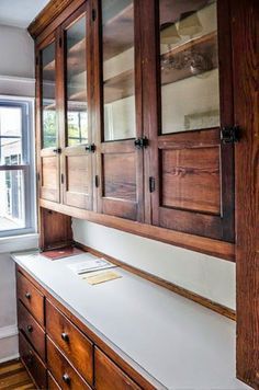 a kitchen with wooden cabinets and white counter tops in front of a large open window