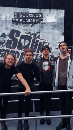 five men are posing for a photo in front of a poster that says 5 seconds of summer