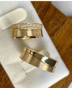 two gold rings sitting on top of a white napkin next to each other in a box