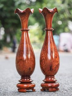 two wooden vases sitting side by side on the ground