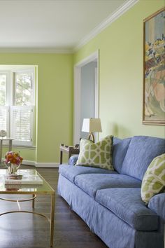 a living room with green walls and blue couches in front of a coffee table