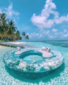 an outdoor hot tub in the middle of water with palm trees and blue sky behind it