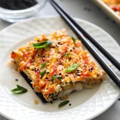 a white plate topped with food next to chopsticks