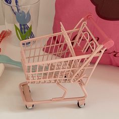 a pink toy shopping cart sitting on top of a table next to a toothbrush