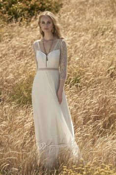 a woman in a long white dress standing in tall grass with her hands on her hips