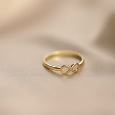 14K Gold Infinity Ring: A simple infinity sign to symbolize eternal and everlasting love, this minimalist ring will make the perfect birthday gift, Valentine's day gift, or Mother's day gift for all of the special people in your life.  Materials & Specifications: - 14K gold ring - Infinity symbol is 4.5mm   As with all of our products, this item is handmade and made to order. **WEARING YOUR JEWELRY** Show your love to your beautifully handcrafted pieces!  Although we stand behind the craftsmanship of our jewelry, our pieces are delicate and not made to be worn during sports and activities such as cleaning and gardening.  When wearing thin/dainty chain bracelets, take care to avoid getting them caught (e.g. on knit sweaters, blankets, or while searching for items in a purse or shopping bag, Infinity Ring For Couple, Infinity Rings Gold, Infinity Gold Rings For Women, Infinity Hand Sign, Minimal Ring Design, Infinity Gold Ring, Minimalist Infinity Promise Ring, Infinity Midi Rings For Anniversary, Anniversary Infinity Midi Rings