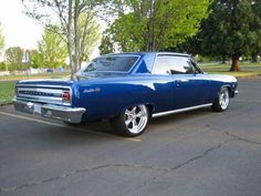 an old blue car parked in a parking lot