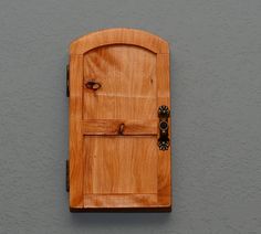 a wooden door on the side of a gray wall with an iron handle and knobs