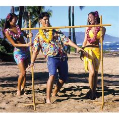 two women and a man are walking on the beach with sticks in their hands,