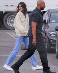 a man and woman walking across a parking lot