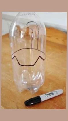 a glass bottle with a face drawn on it and a marker sitting next to it