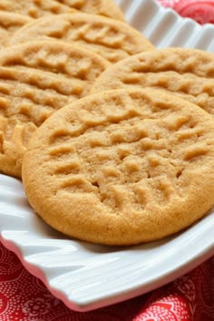 two peanut butter cookies on a white plate with red and white table cloth behind them