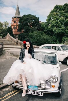 a woman in a white dress sitting on top of a car