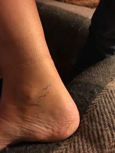 a close up of a person's foot with a small tattoo on the ankle