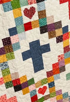 a quilt made with different colored squares and hearts on the front, as well as a cross in the middle